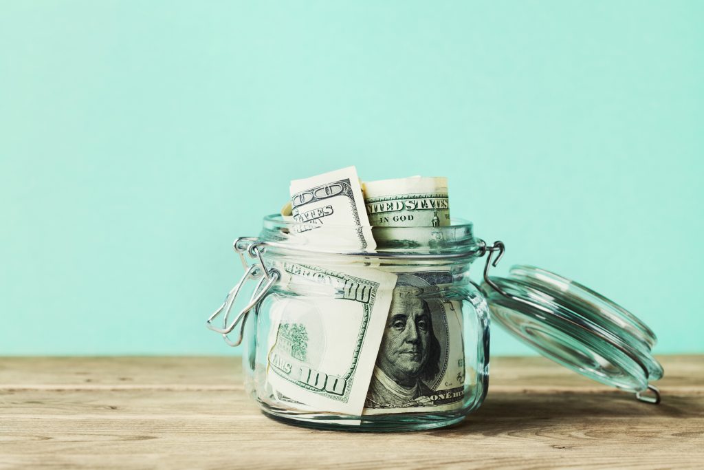 an image of a jar filled with money on a light teal background on a post from Not Quite an Adult about the 30 Day Rule 
