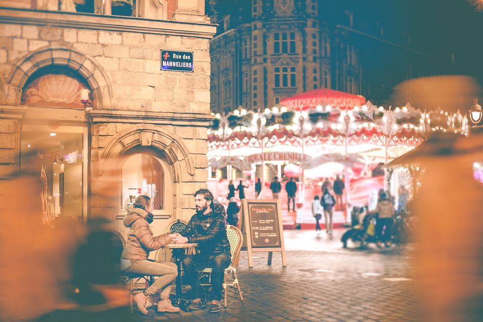 An image of two people on a date sitting at a cafe with a carousel in the background 